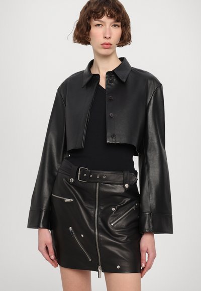 Črni usnjeni jakna na voljo s pritiskačem in dolgimi rokavi, v kombinaciji s črno usnjeno mini krilom, ki ima zadrge in pas.