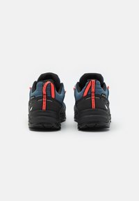 Blue and black hiking shoes with red accents, mesh upper, textured sole, and prominent heel counter; designed for outdoor performance.