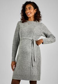 Abito grigio lavorato a maglia con motivi a treccia, maniche lunghe, scollatura rotonda e una cintura annodata in vita. Texture morbida con polsini e orlo a coste.