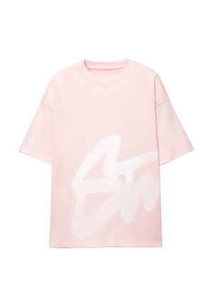 Lyserød oversized t-shirt lavet af bomuld, med et stort hvidt abstrakt logo designet på forsiden. Korte ærmer og rund halsudskæring.