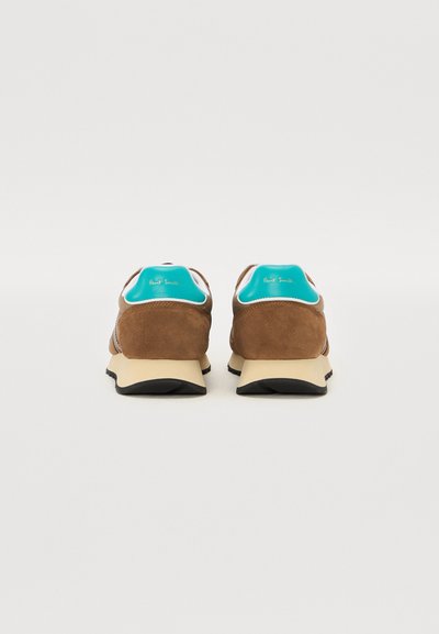 Baskets en daim marron avec des accents turquoise, présentant une semelle beige clair et une semelle extérieure en caoutchouc noir, affichant une forme arrondie et une texture lisse.