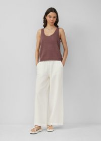 Mauve gebreide tanktop met een V-hals en witte wijde broek, voorzien van een textuurpatroon. Schoeisel omvat beige sandalen met een bandontwerp.