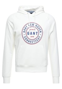 Felpa bianca con cappuccio e tasca a marsupio frontale, caratterizzata da un logo circolare rosso e blu che riporta la scritta "GANT NEW HAVEN CONNECTICUT."