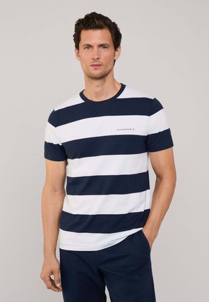 Camiseta de algodón a rayas en azul marino y blanco con un cuello redondo y un logo en el pecho. Manga corta, corte regular, textura suave.
