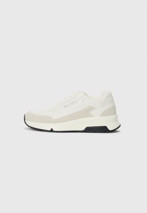 White and beige low-top sneaker with lace-up front, black sole, and "Armani Exchange" branding on side and sole.