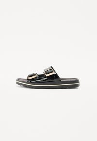 Sandales mules noires en vernis avec double boucles ajustables, semelle rembourrée et semelle en caoutchouc épaisse avec un accent de couleur claire.