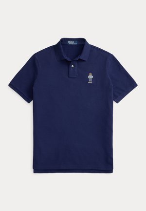 Granatowa koszulka polo z bawełny z listwą na dwa guziki. Posiada haftowane emblem na lewej piersi, krótkie rękawy i prostą linię dołu.