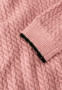 Różowy sweter z dzianiny o teksturowanym wzorze w warkocze. Rękaw posiada żebrowany design z kontrastową czarną krawędzią. Miękki, puszysty materiał.