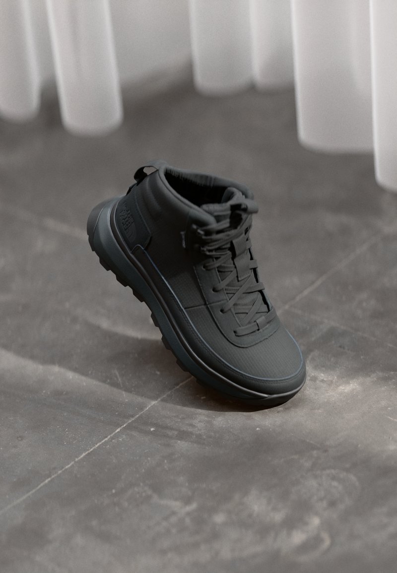 Sneaker alto nero con superficie testurizzata, design con lacci e suola spessa. Presenta un collo rinforzato e un dettaglio logo discreto.