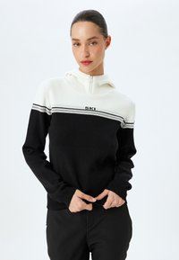 Zwart-witte hoodie met een half-rits ontwerp. Bevat horizontale zwart en grijs gestreepte patronen en "SKI" geborduurd op de borst. Zacht materiaal.