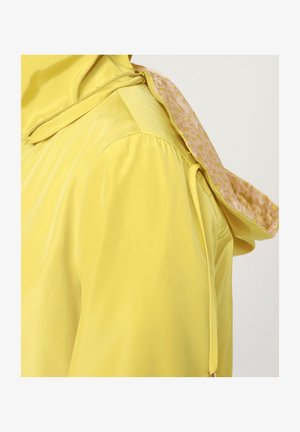 Chaqueta impermeable amarilla con un forro interior texturizado, que cuenta con capucha, puños elásticos y un cierre de cremallera en el cuello.