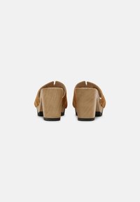 Tan suède klompen met een houten hak. Open achterkant ontwerp, vierkante hakvorm, gladde textuur en minimale stikseldetails.