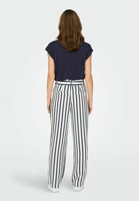 Camisa azul marino de manga corta combinada con pantalones blancos de cintura alta que presentan rayas verticales en azul marino; tejido suave, corte relajado y bolsillos laterales.