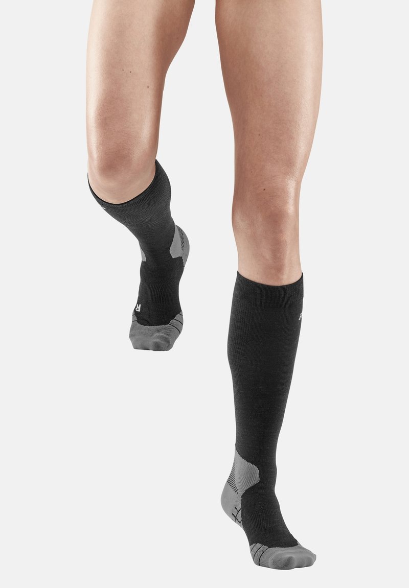 Knielange schwarze Socken mit strukturiertem Oberteil, kontrastierendem grauem Zehen- und Fersenbereich sowie gepolsterten Bereichen für Unterstützung. Hergestellt aus atmungsaktivem Material.