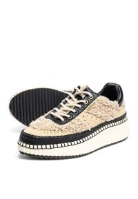Chunky sneakers met een beige en zwarte kleurenschema. Bovenkant heeft een pluche textuur met suède en leren accenten. Dikke, geribbelde zool.