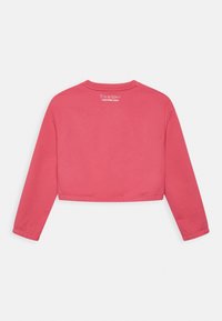 Różowy krótki dres z długimi rękawami, okrągłym dekoltem i białym napisem "To jest miłość Calvin Klein Jeans" wydrukowanym na dekolcie z tyłu.