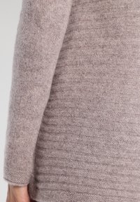 Sweter wykonany z dzianiny w miękkim, jasnym kolorze mauve, z teksturowanym wzorem poziomych pasków. Posiada długie rękawy i luźny krój.