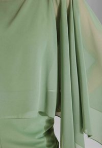 Fließendes grünes Chiffon-Top aus weichem, durchsichtigem Stoff; weite Ärmel fallen elegant; eine glatte, leichte Textur hebt das Design hervor.