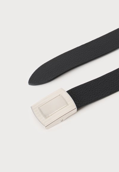 Ceinture en cuir noir texturé avec une boucle rectangulaire en métal argenté sur fond clair uni.