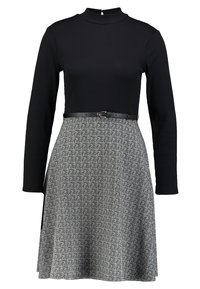 Svart långärmad klänning med ribbat överdel och en utsvängd kjol i fiskbensmönster, åtdragen med ett svart bälte i midjan.