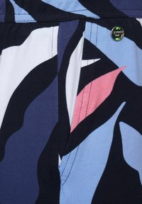 Badshorts med ett djärvt abstrakt mönster i marinblått, blått, rosa och vitt. Tillverkade av lätt tyg med synliga sömmar och detaljer i metall.