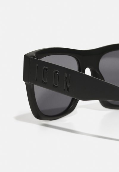 Occhiali da sole neri con il bold "ICON" logo sul lato, montatura squadrata, lenti scure e finitura opaca. Materiale plastico, design elegante.