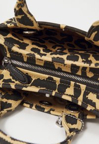 Leopárdmintás textilekből készült kézi táska fekete akcentusokkal, cipzáras záródással és kis lánc részletekkel a pánton. Belső tér látható.