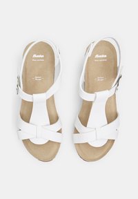 Weiße Ledersandalen mit einem Riemen-Design, ausgestattet mit einem Schnallenverschluss und einer strukturierten beigen Fußbett. Glatte Materialien mit einem minimalistisch wirkenden Look.