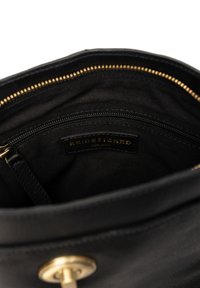 Vnitřek černé kožené kabelky s kapsou na zip, zlatým zipem a štítkem s vyraženým nápisem "RE:DESIGNED EST.2013." Měkké látkové podšívání.