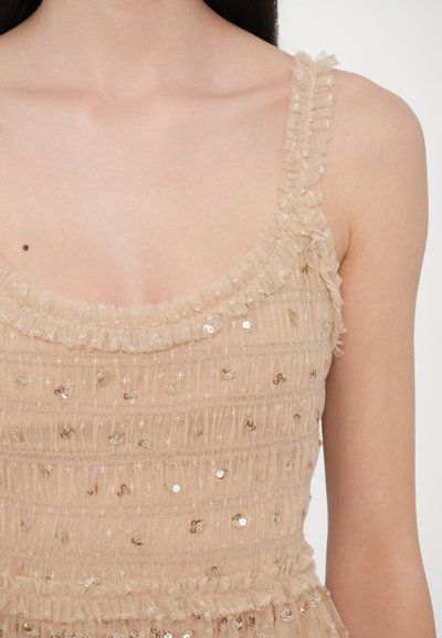 Abito color nudo con tessuto strutturato, spalline volant e dettagli in paillettes. Scollo piatto e vita arricciata per definire la silhouette.