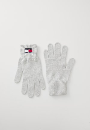 Hallid hallid kinnased ribatud randmeteäärega, millel on must, punane ja valge "TOMMY JEANS" logo silt randme ääres. Sile tekstuur, tavaline viie sõrme disain.
