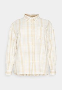 Camisa de botão quadriculada em branco e amarelo claro. Mangas longas, colarinho, bolso no peito e um ajuste descontraído com uma bainha arredondada. Tecido de algodão.