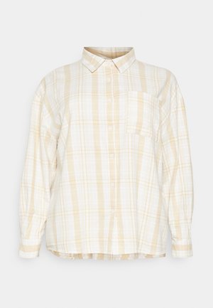 Camisa de botão quadriculada em branco e amarelo claro. Mangas longas, colarinho, bolso no peito e um ajuste descontraído com uma bainha arredondada. Tecido de algodão.