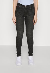 Svarta slim-fit jeans i denim, med hög midja, klassisk femficksdesign och subtila sömdetaljer. Matchas med vita sneakers.