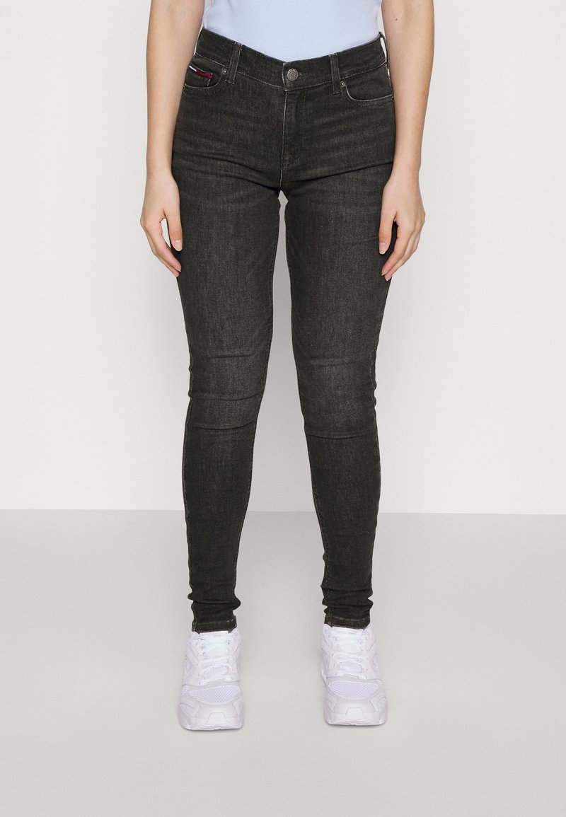 Svarta slim-fit jeans i denim, med hög midja, klassisk femficksdesign och subtila sömdetaljer. Matchas med vita sneakers.