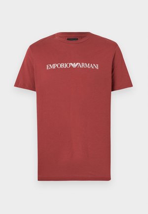 Punane puuvillane T-särk, millel on rindkeres valge "EMPORIO ARMANI" logo, lühikesed varrukad ja klassikaline ümar kaelus.