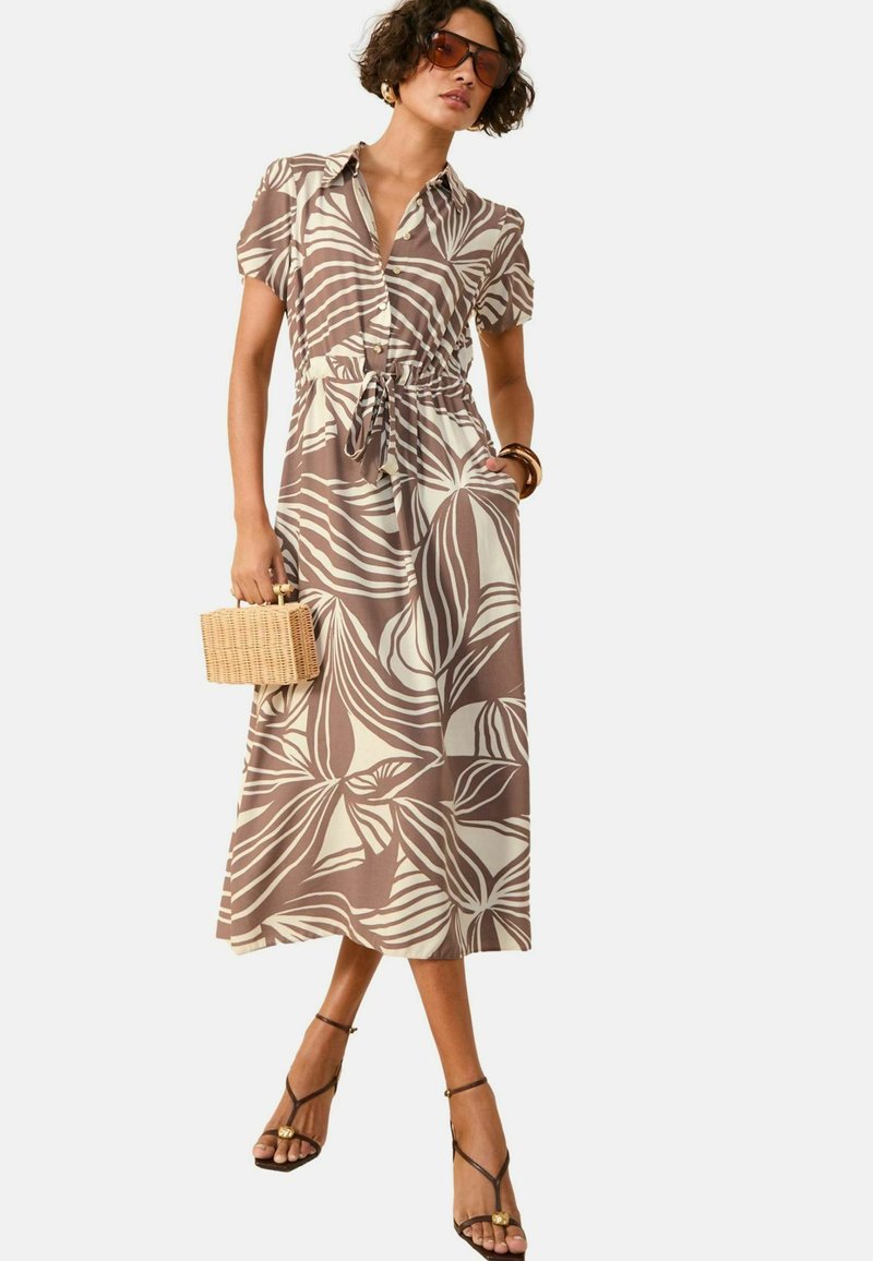Beige maxi kleit tumepruunide troopiliste lehtede mustriga, lühikesed puffkäised, nupud, reguleeritav vöö ja taskud. Kombineeritud rihmikute sandaalidega.
