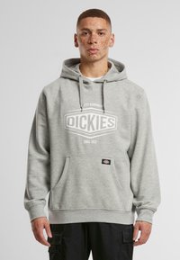 Szürke kapucnis pulóver, elülső zsebbel, fehér logóval, amelyen a "DICKIES" felirat található. Puha anyagból készült, húzózsinórral ellátott kapucnival és bordázott mandzsettával.