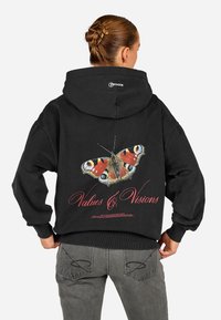 Sweatshirt preto com um grande design de borboleta nas costas, com o texto "Valores & Visões" abaixo. Tecido suave, corte relaxado, punhos com nervuras.