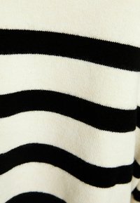 Tessuto a maglia a righe orizzontali bianco e nero con una texture morbida e pelosa.