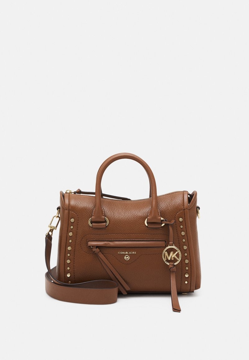 Brązowa skórzana torebka Michael Kors z podwójnymi uchwytami, przednią kieszenią na zamek błyskawiczny, złotymi ćwiekami i odczepianym paskiem na ramię na białym tle.