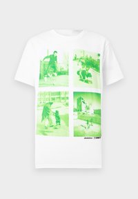 Λευκό μπλουζάκι με τέσσερις φωτογραφίες με πράσινη απόχρωση που δείχνουν ανθρώπους να κάνουν σκέιτμπορντ και να περπατούν σε υπαίθριους αστικούς χώρους.