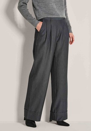 Weite, gestreifte Hose in Dunkelgrau, aus glattem Stoff. Mit vorderen Falten und gerollten Säumen. Das Modell trägt einen grauen Pullover.