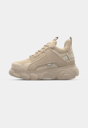 Beige színű sneaker, szintetikus és textil felsőrésszel, kerek orral, vastag talppal és oldalsó márkajellel. Texturált elemekkel és fűzős záródással rendelkezik.