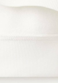 Tissu de sweatshirt en coton blanc avec poignets côtelés en bas. Texture douce avec une doublure intérieure légèrement duveteuse. Sans motifs ni accents.