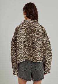 Cropped leopard print jacket made of soft fabric, featuring a large collar and long sleeves, paired with black denim shorts.