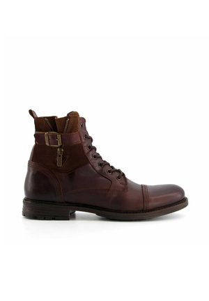 Bruine leren enkelboots met een gladde afwerking, vetersluiting aan de voorkant, zijrits en gespdetail op de schacht. Platte zool en ronde neus.