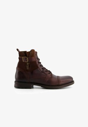 Brown leather ankle boot with a smooth finish, lace-up front, side zipper, and buckle detail on the shaft. Flat sole and rounded toe.