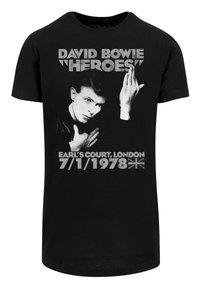 Black t-shirt featuring a graphic of a person with a hand gesture, text reading "DAVID BOWIE 'HEROES!'" and event details printed below.