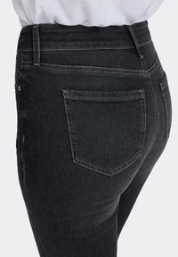Jeans i mörk tvätt gjorda av denim, med hög midja, smal passform och bakfickor med subtila sömnadsdetaljer.